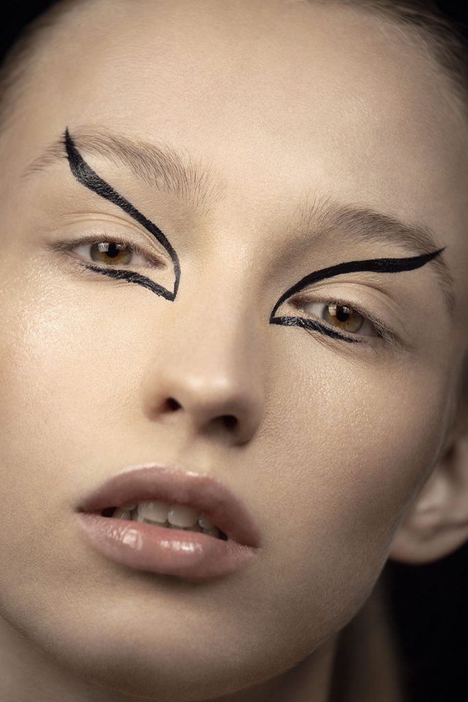 Close-up of model's face with black avant-garde eye make-up.