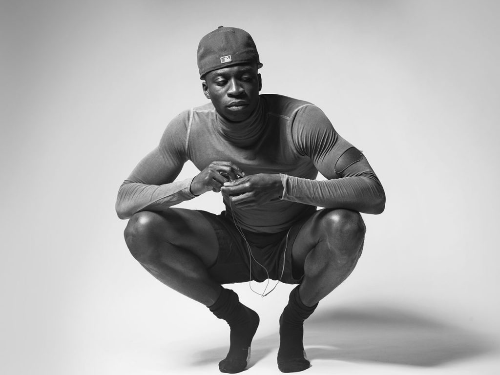 Athletic black man squatting on the floor.