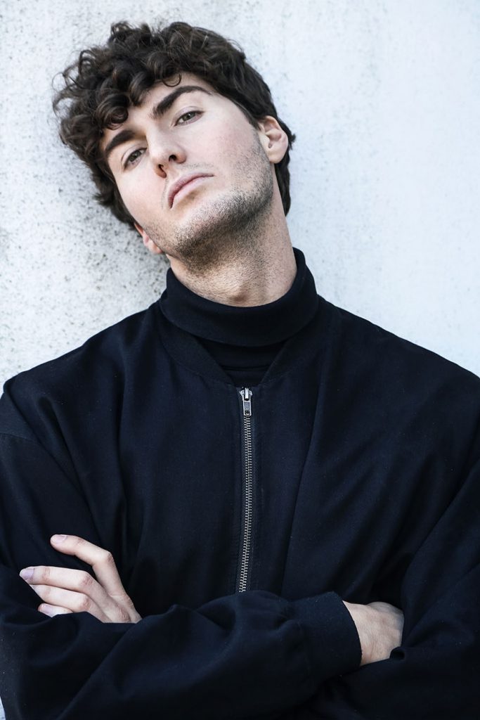 Portrait of male model in black jacket with crossed arms.